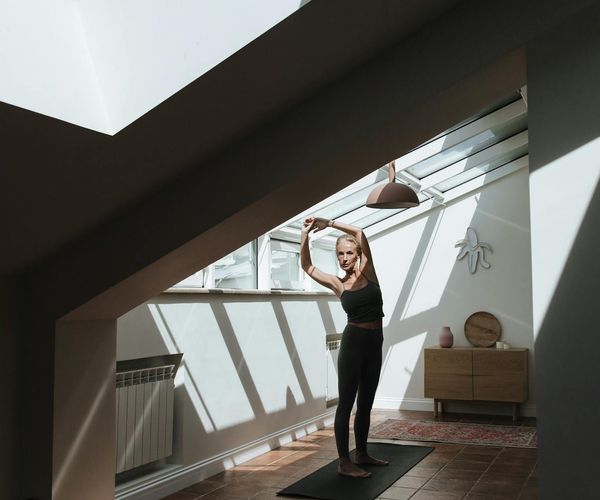 Woman peacefully stretching in a bright, sunlit room.